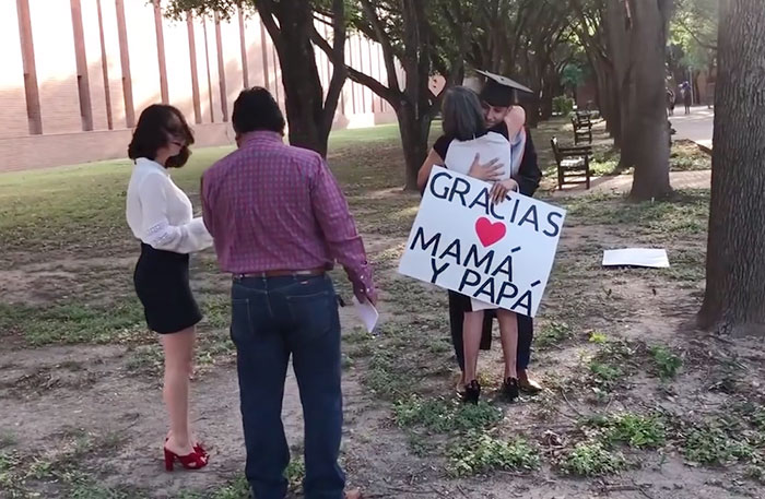 Immigrants parents hug their graduating son.