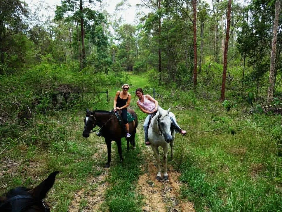 A photo of Holly with a friend riding a horse.