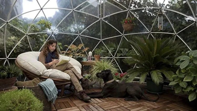 A woman reading inside a garden igloo