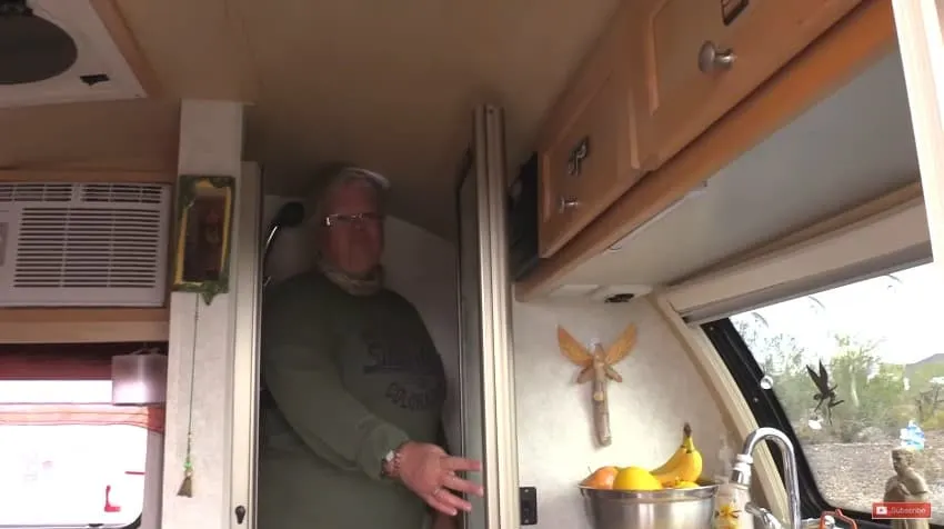 Woman shows camera the inside of her tiny teardrop trailer home.