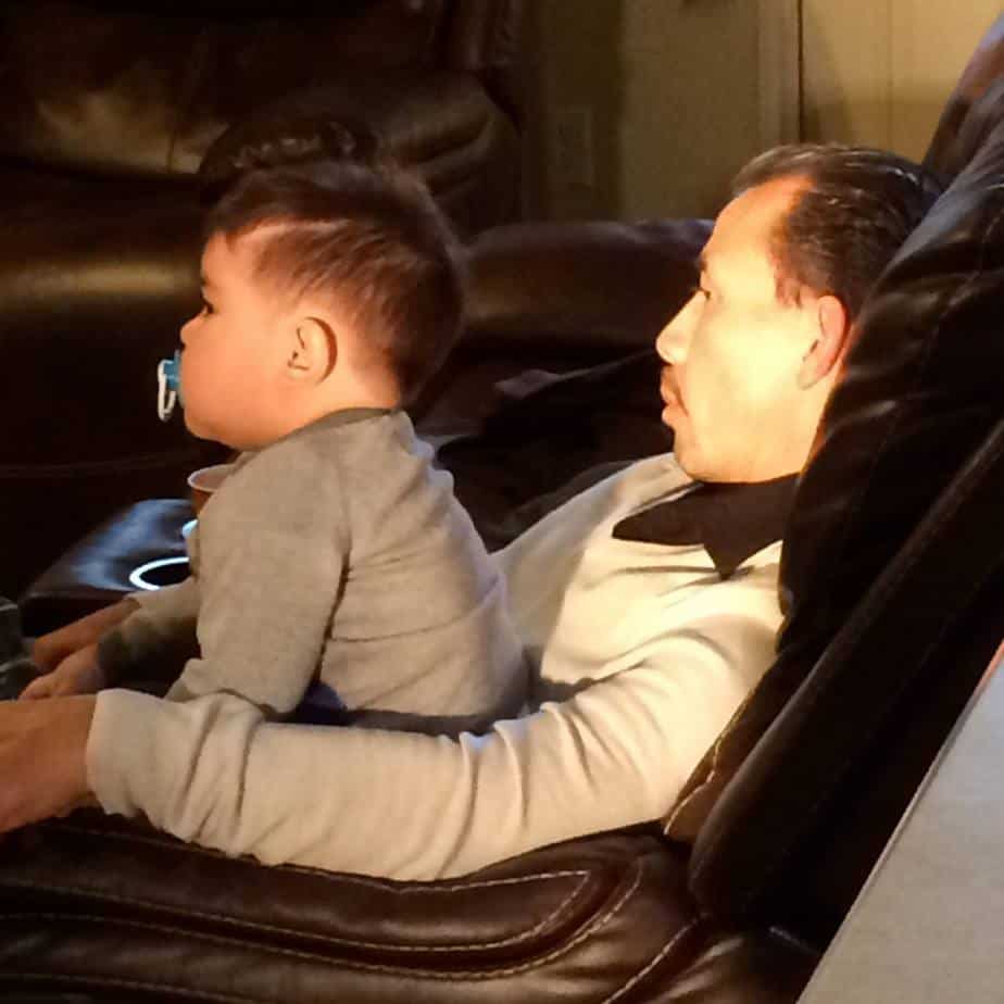 Grandchild with his doting grandpa watching a TV show.