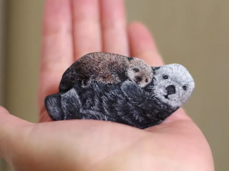 An image of an otter mother and offspring painted on a stone by Akie Nakata