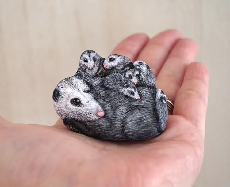 An image of an opossum family painted on a stone by Akie Nakata