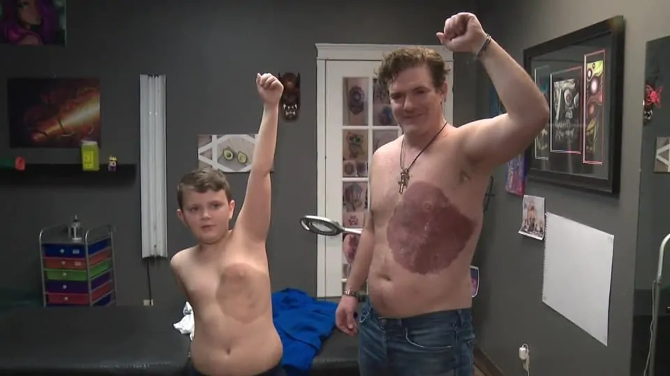 dad and son with identical tattoos raising their arms