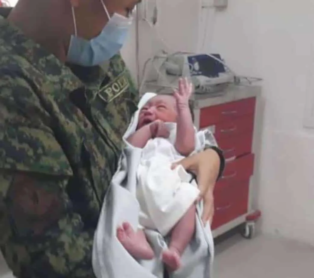 A militay personnel holding a newborn baby boy