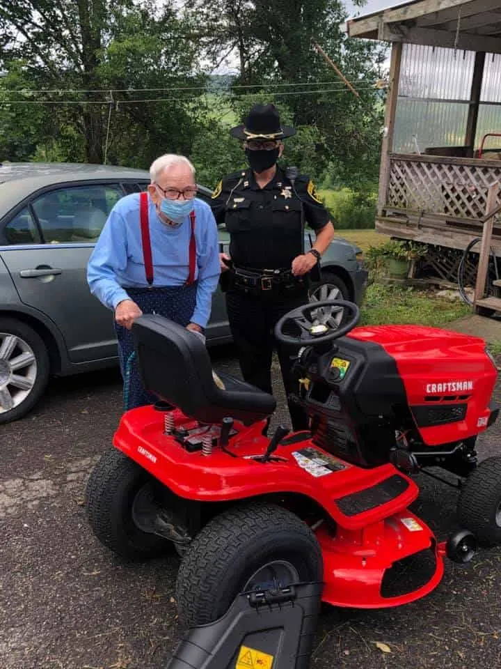 Gordon Blakeslee and a police officer standing behind a brand new mower