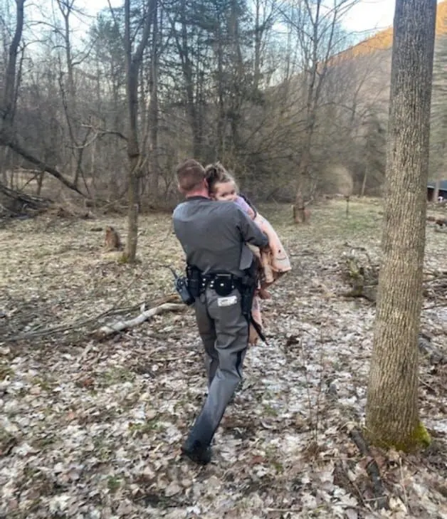Trooper Brian Hotchkiss going down the hill while carrying a little girl in his arms