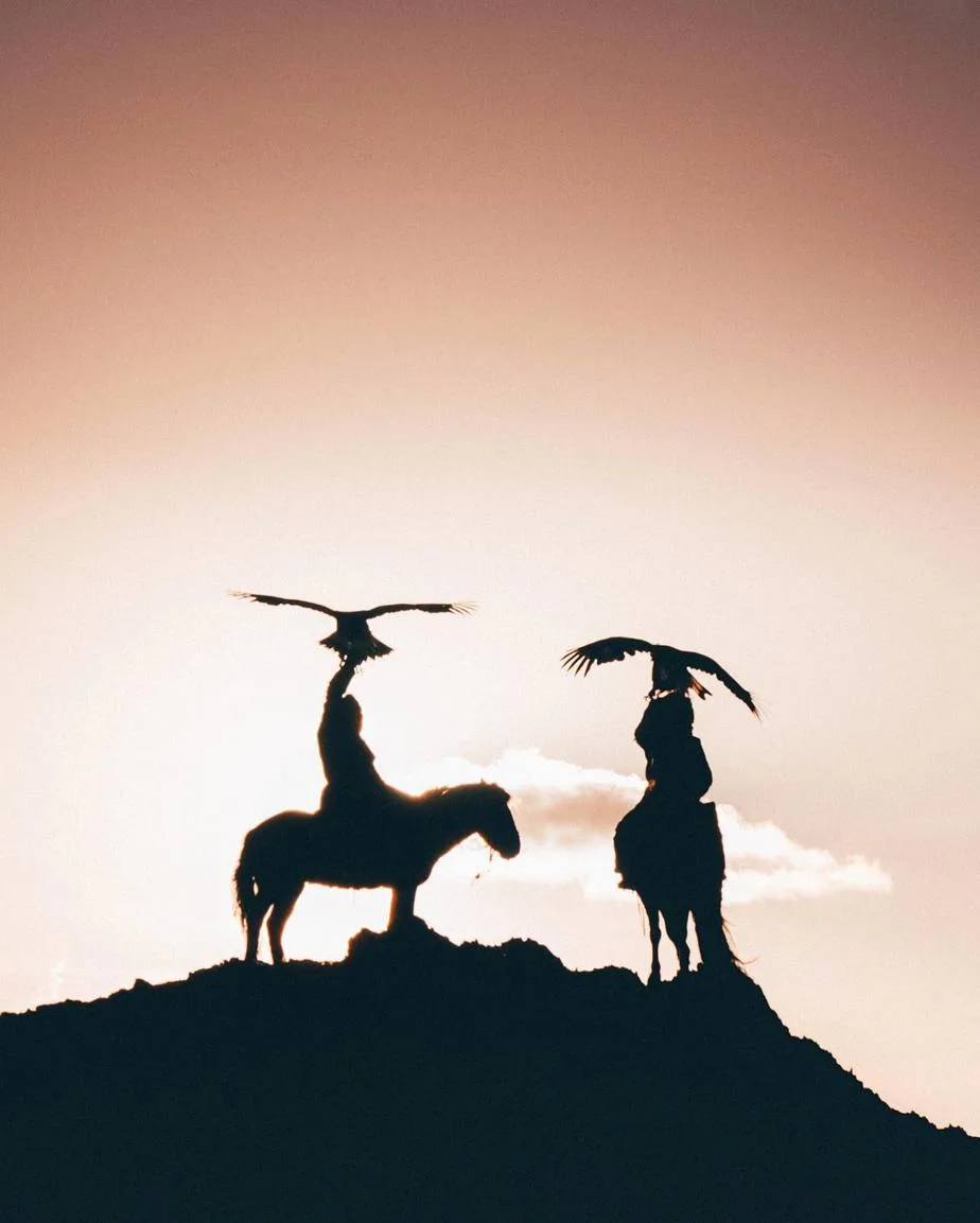 A silhouette of two eagle hunters and their eagles