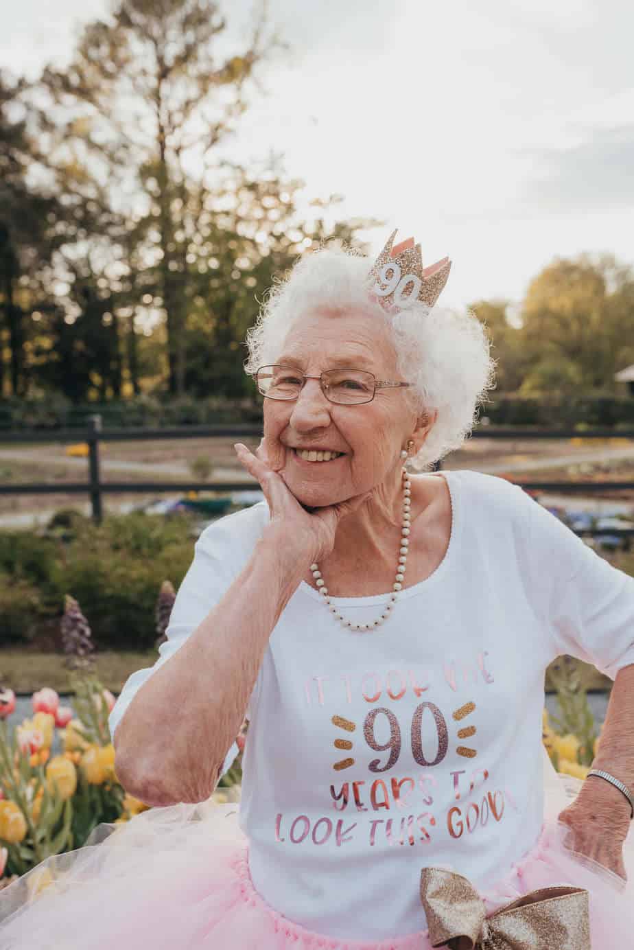 A smiling grandma wearing a pink crown and tutu