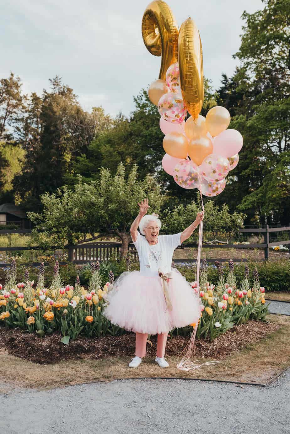 A grandma wearing a pink tutu while holding balloons
