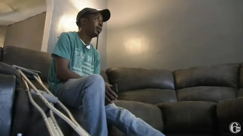 Jermaine sitting on a couch with his crutches by his side