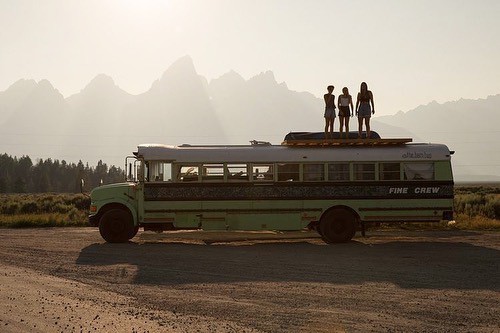 Three women standing on top of a school bus