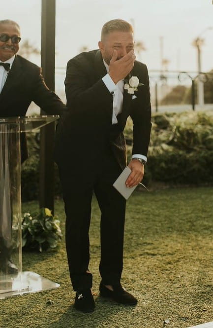 Jay Bloomfield covering his mouth with his hand while crying after seeing his bride walking down the aisle