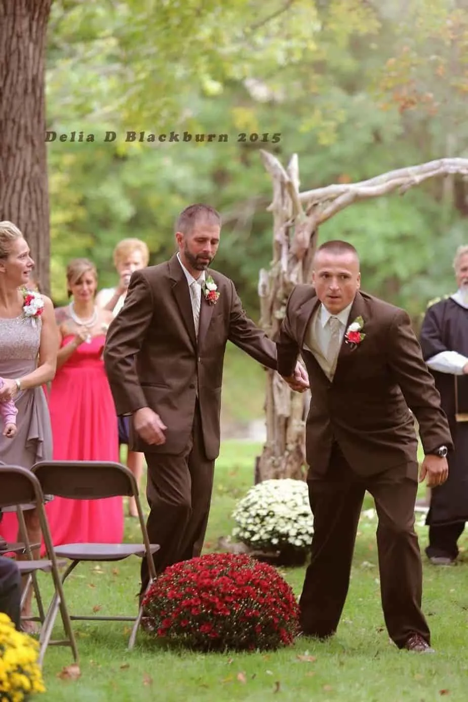 A father-of-the-bride grabbing his daughter's stepdad by the hand so he can walk with them down the aisle