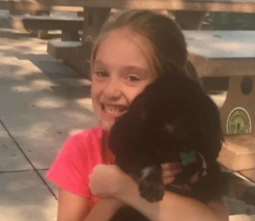 Loralie Henry holding a black puppy 