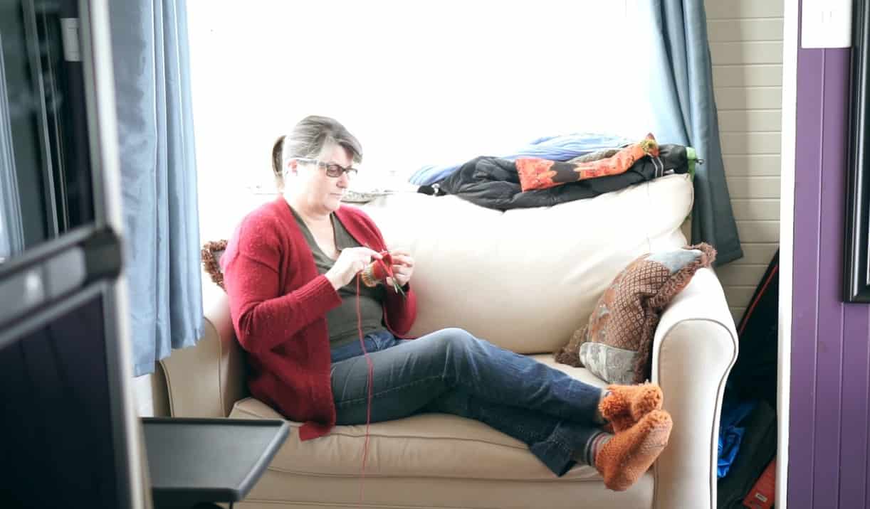 Christine knitting while sitting on her living room sofa
