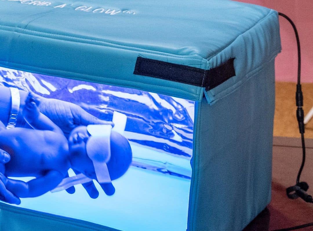 A dummy newborn being placed inside a Crib A'glow