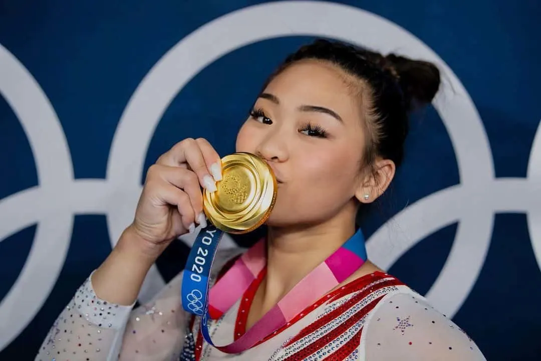 Suni Lee kissing her Olympic gold medal