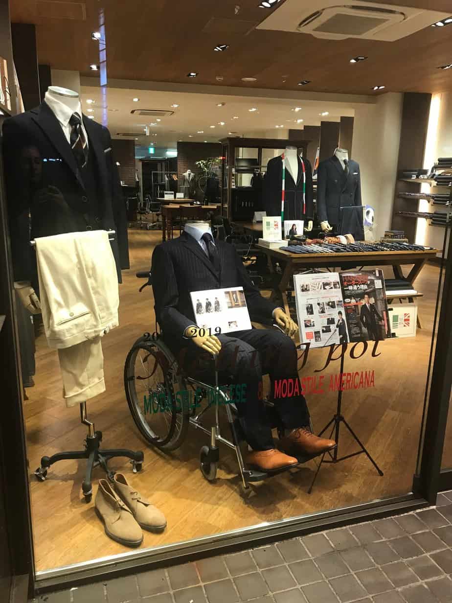 A suit shop in Tokyo displaying one of their suits with a mannequin seated on a wheelchair