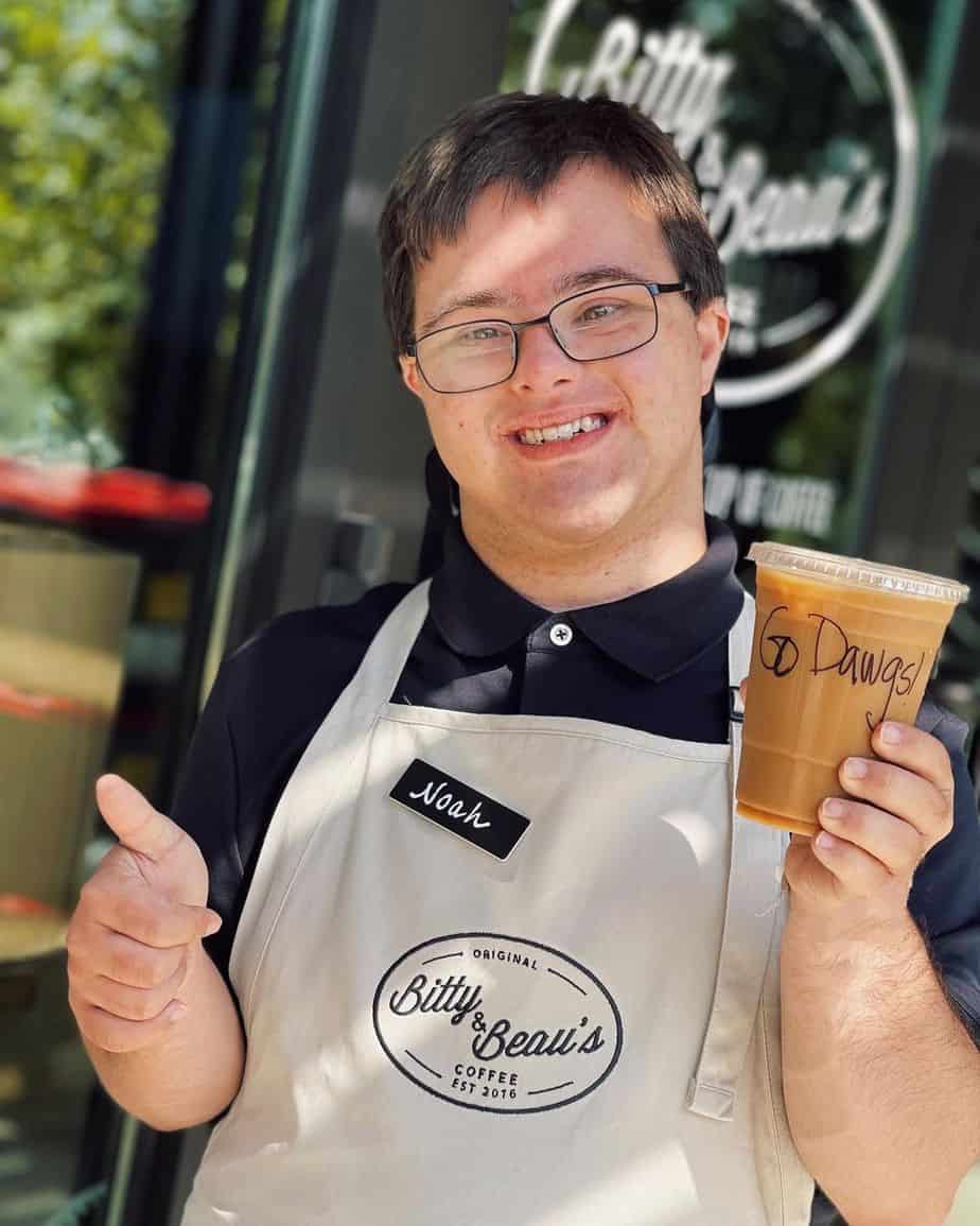 A Bitty and Beau's employee named Noah holding a coffee drink in his hand