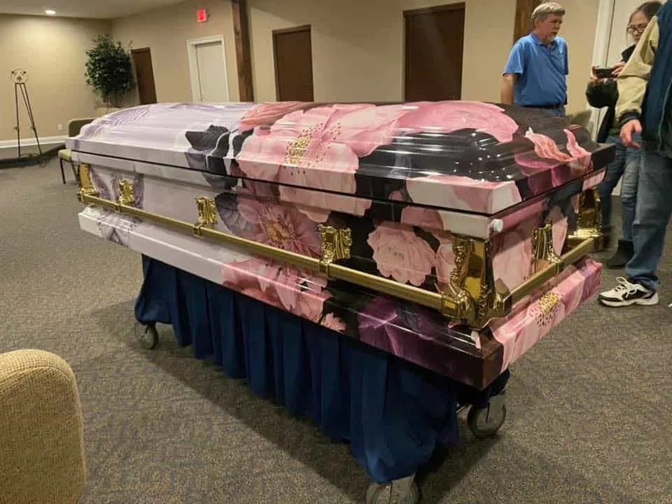 A wrapped casket decorated with images of pink flowers 