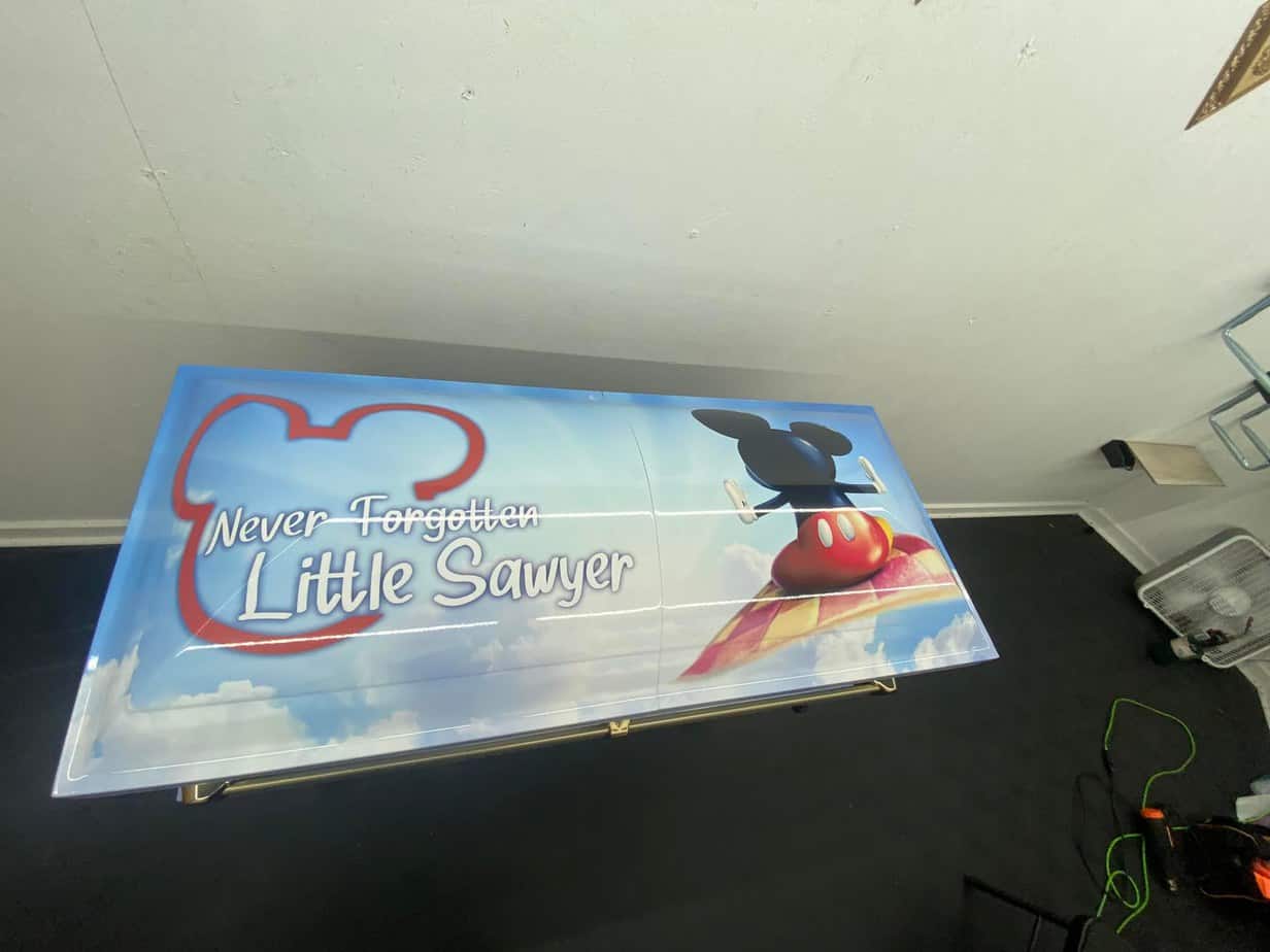 A small casket wrapped with an image of Mickey Mouse on a floating carpet in the clouds