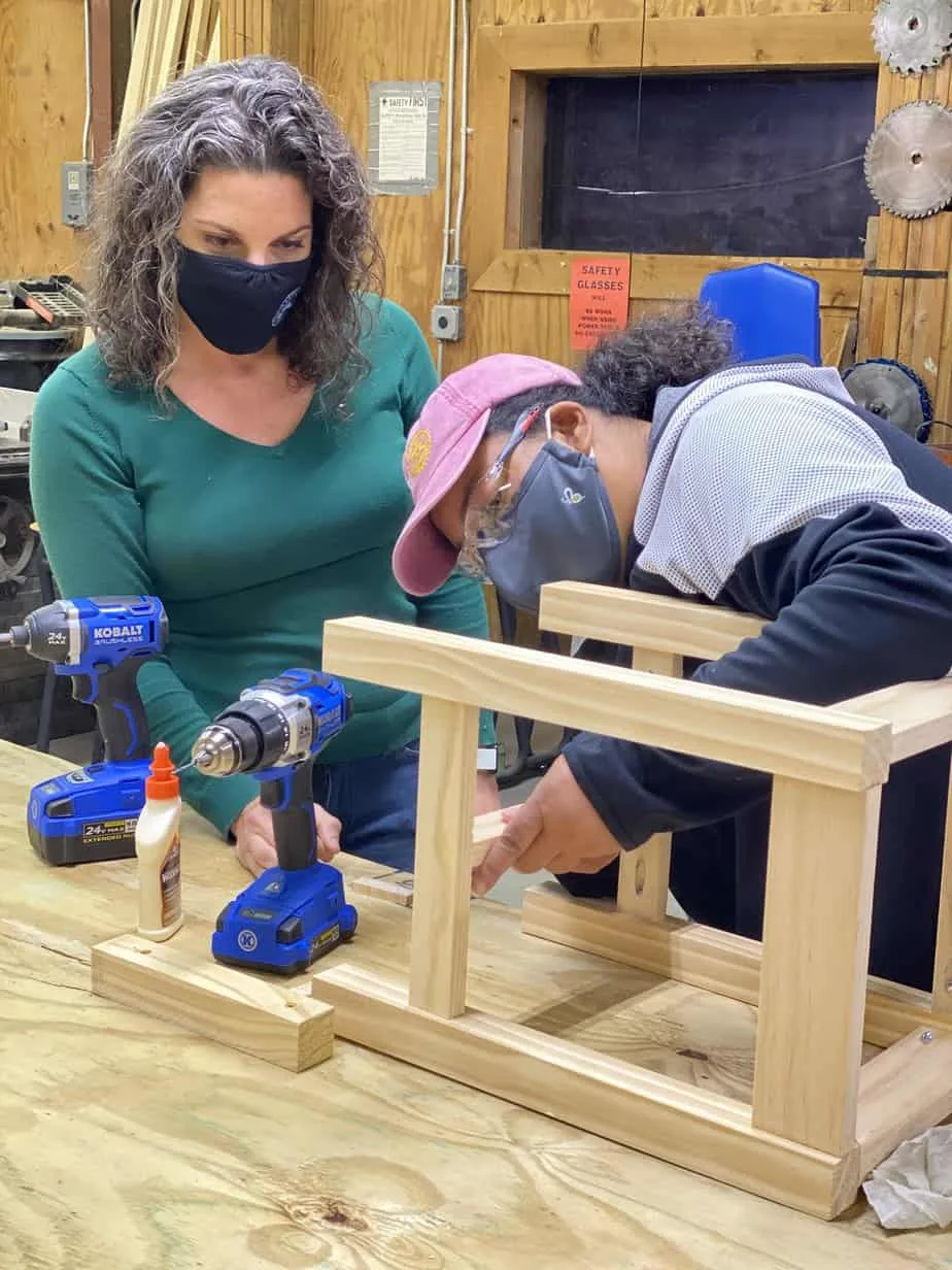 Nora El-Khouri Spencer teaching a woman woodworking