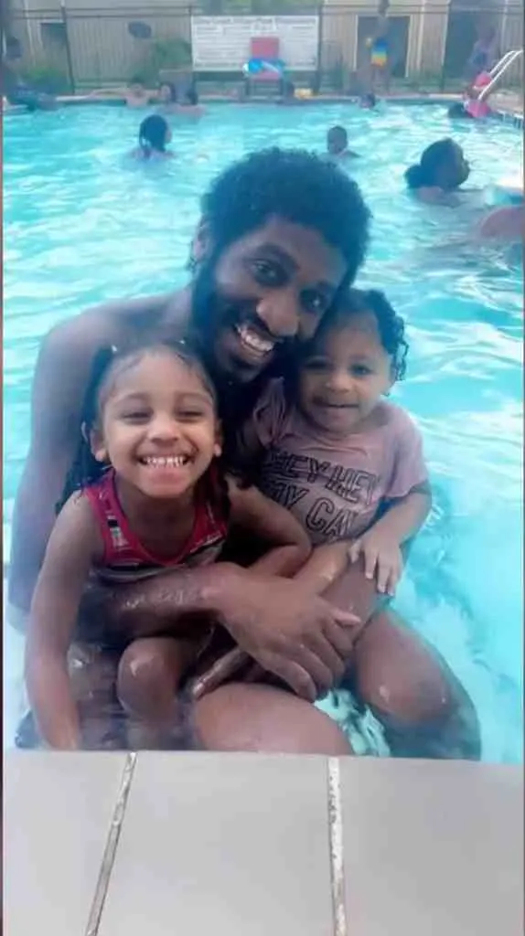 Devonte hugging his two daughters and smiling for a photo.