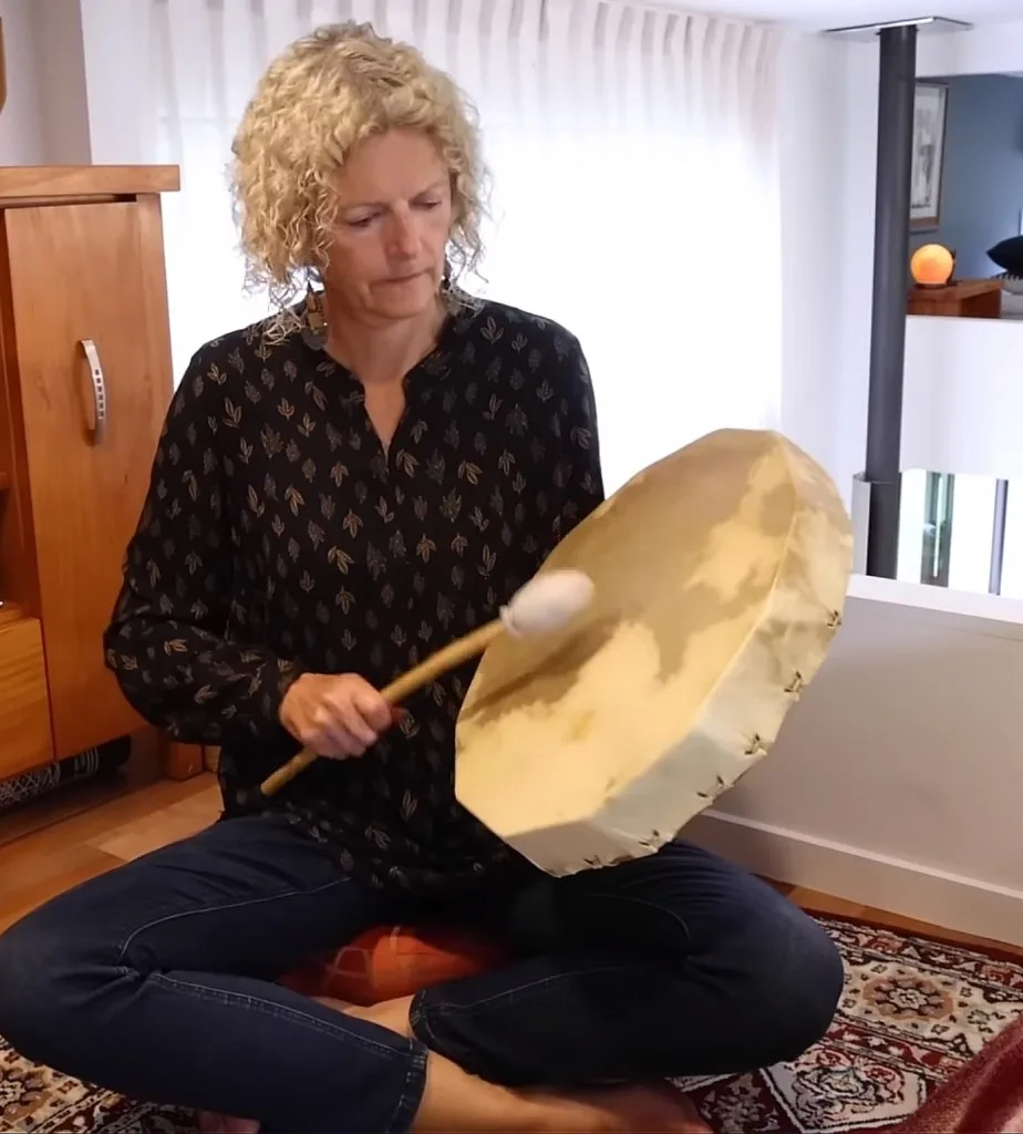 Christine playing her drum on the other loft of her off-grid living forest tiny house.