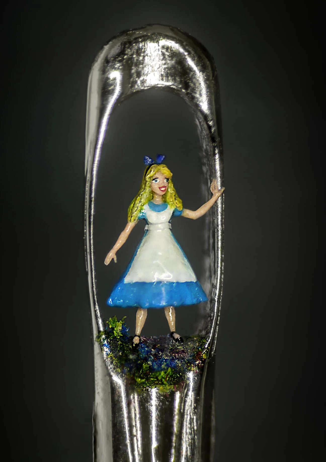 Tiny Alice in Wonderland sculpture in the eye of a needle.