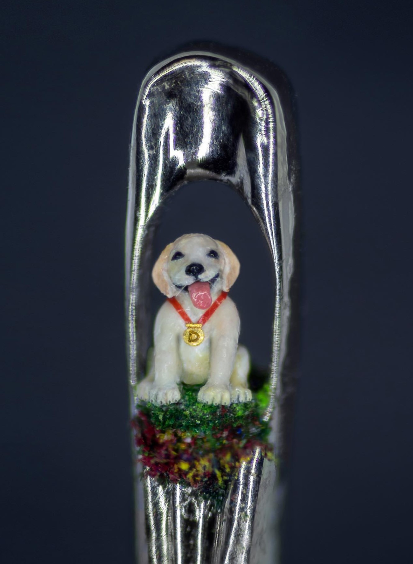 Miniature dog sculpture in the eye of a needle.