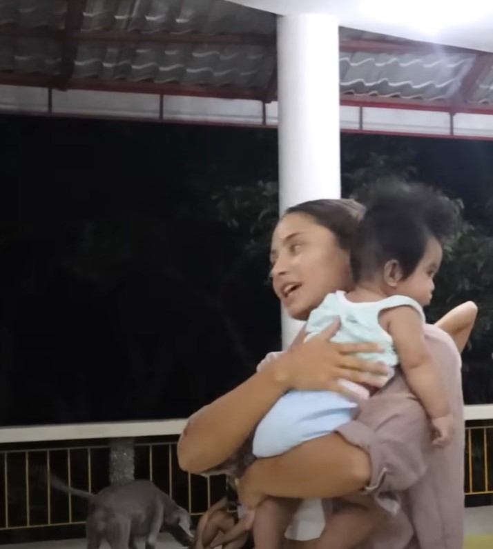 The writer carrying a baby while volunteering at an orphanage.