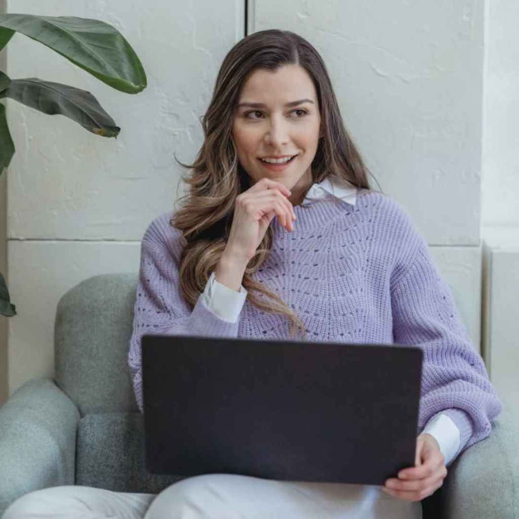Woman, working on her laptop while smiling and full of positivity.