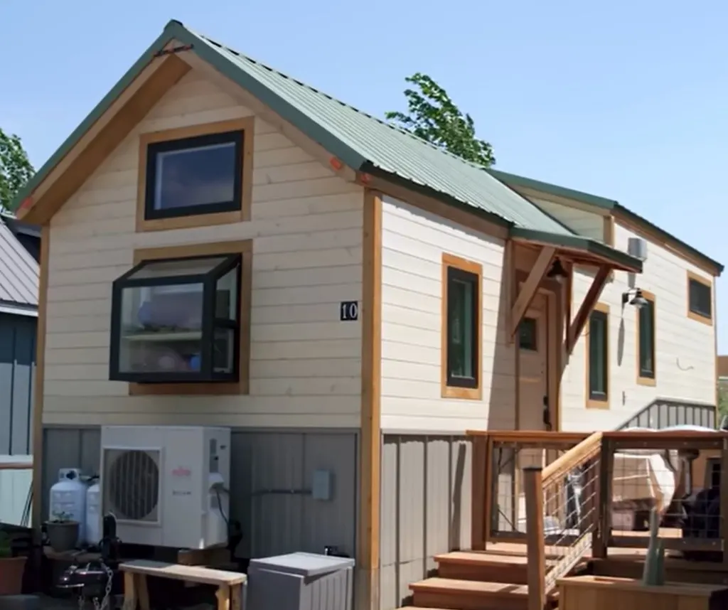 The tiny house retirement home has yellow paint with a green rooftop.