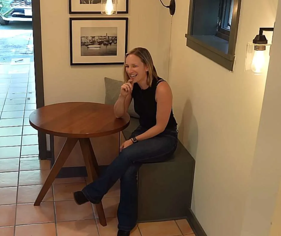 Emily Cangie sitting on the bench by the coffee table at the "captain's quarter."