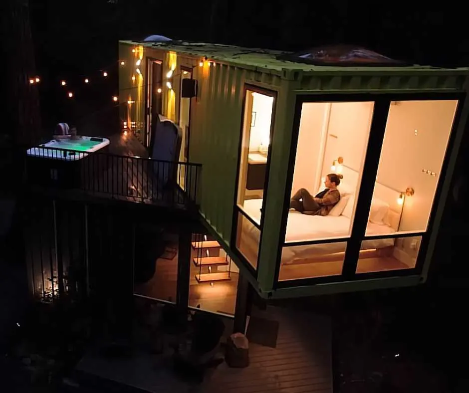 Nick's luxury eco-friendly home at night with a man in tub and a woman on bed in the guestroom.