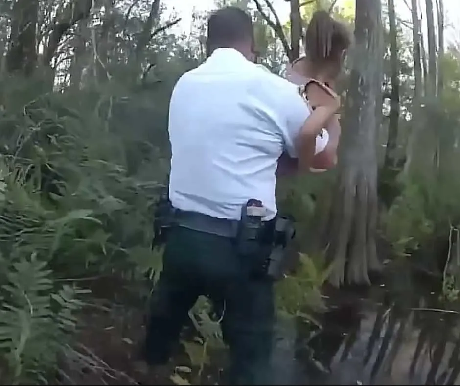 Officer carries the girl with autism out of the swamp.