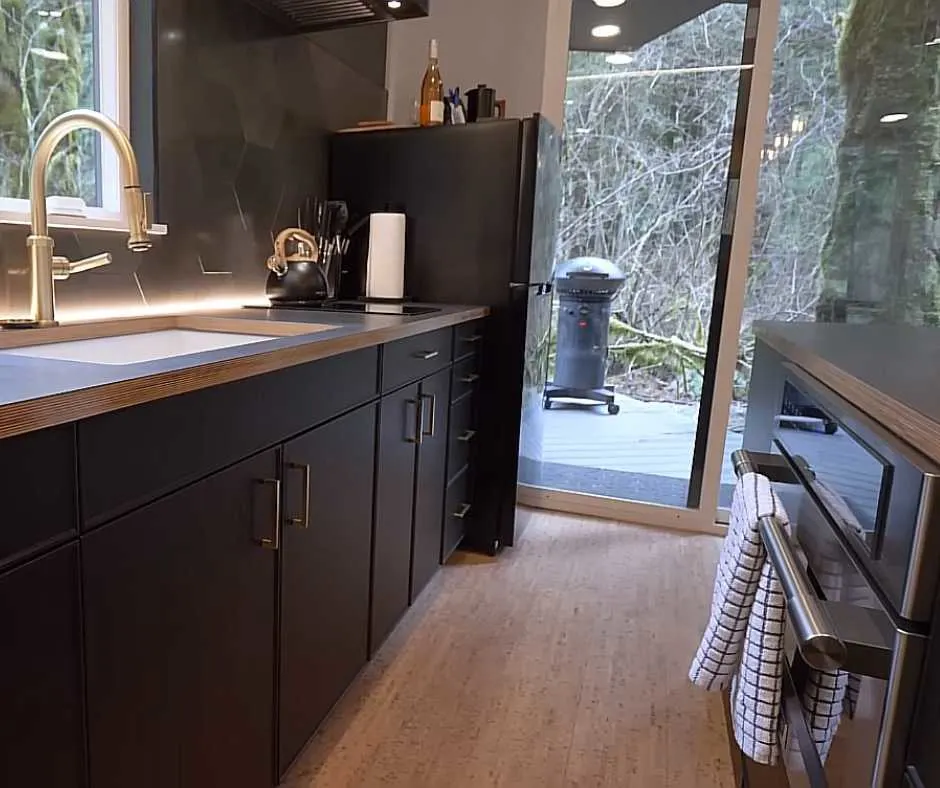 The kitchen at Nick's container home with sink, fridge, oven, and stove.