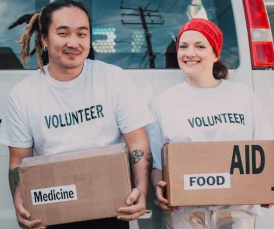 Two volunteers holding boxes of food and medicine