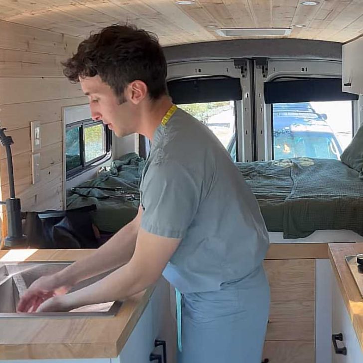 Ethan washing his hands inside his mobile dorm, a Ford Transit van conversion