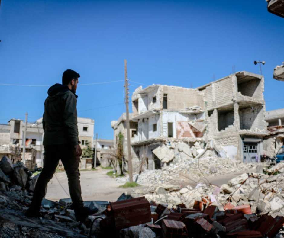 Man walking by the broken house after an earthquake in Syria