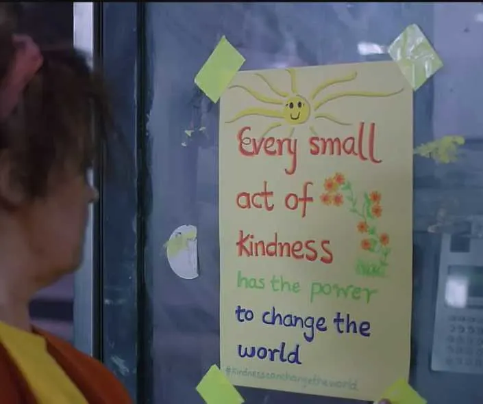 Woman puts a poster that says every small act of kindness has the power to change the world