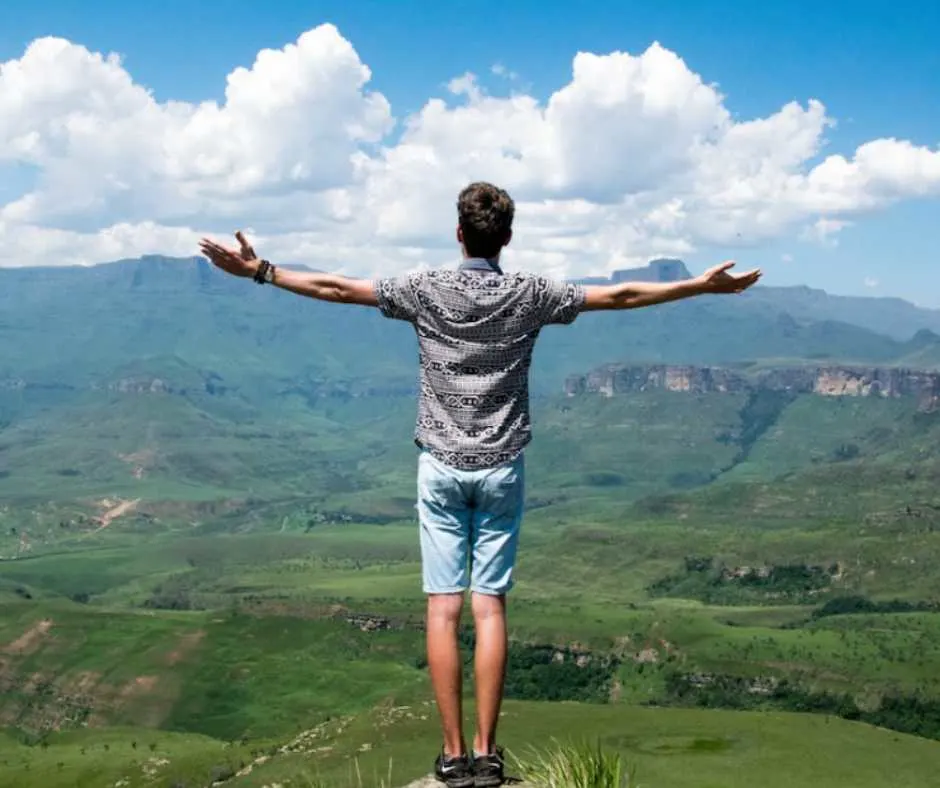 Man standing by the cliff with arms wide open