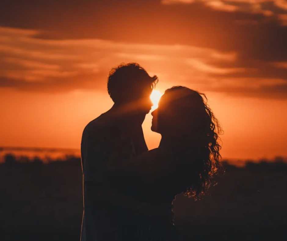 Silhouette of man and woman hugging each other as the sun sets