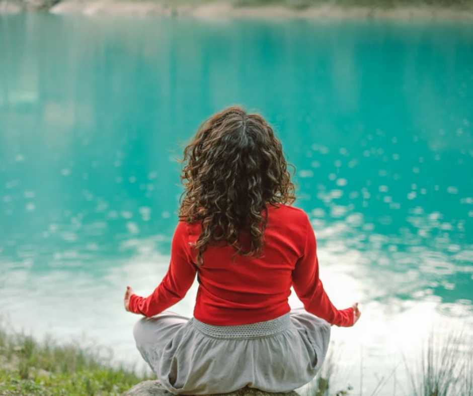 Woman meditating alone by the lake