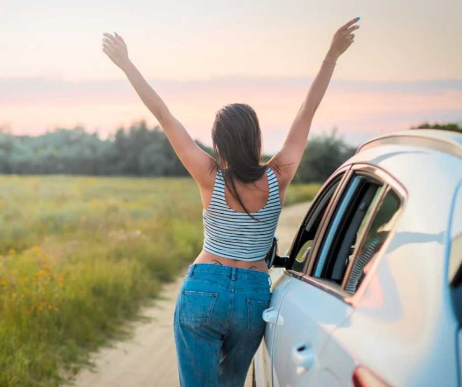 Woman standing by her car and raising her hand
