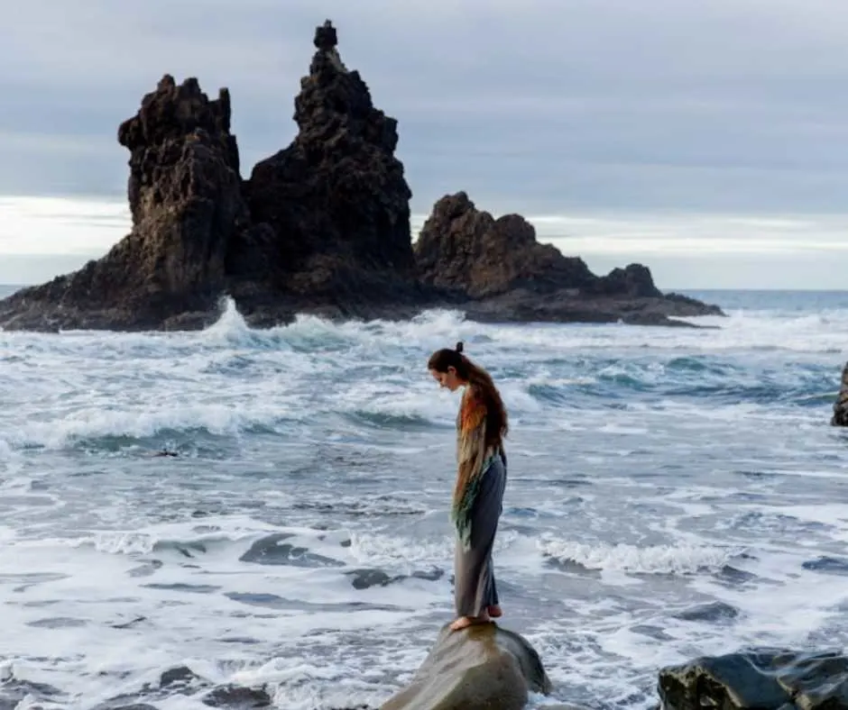 Woman standing on a rock by the beach