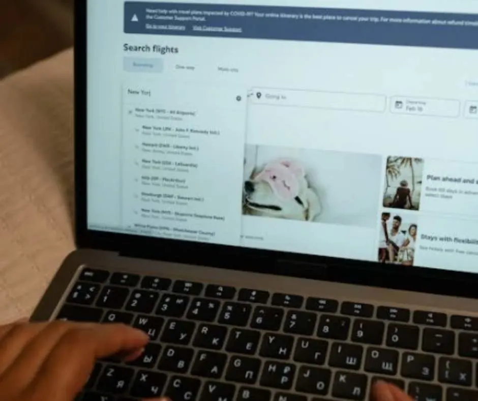 Fingers on laptop browsing for flights